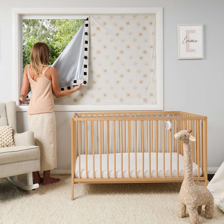 Mother installing portable blackout blind in baby nursery