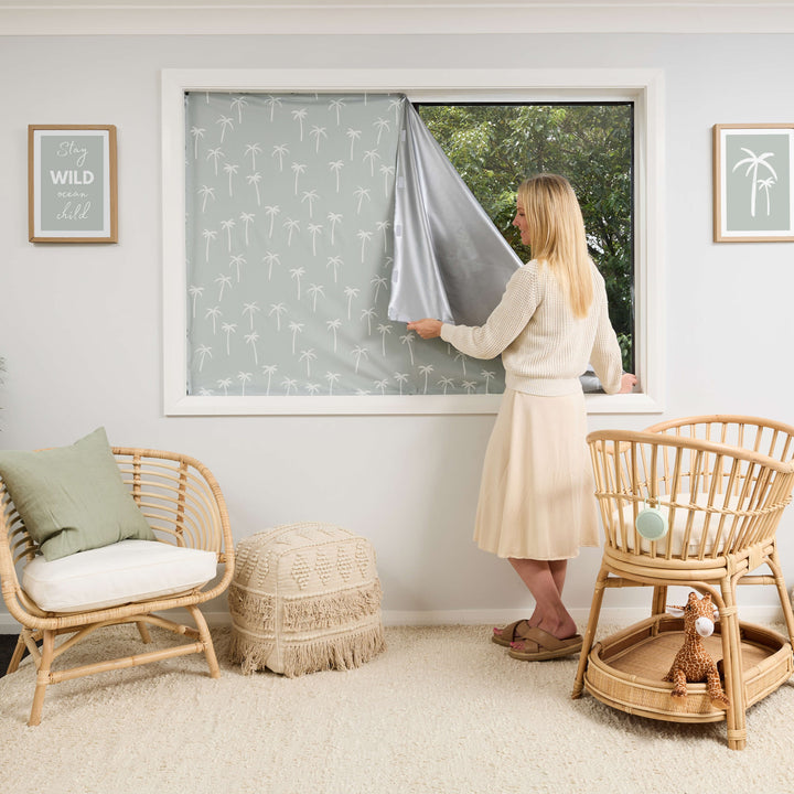 Customisable blackout blind with velcro that attaches to the window and the curtain. Greyish green with palm tree design. Perfect for nursery or bedroom. 